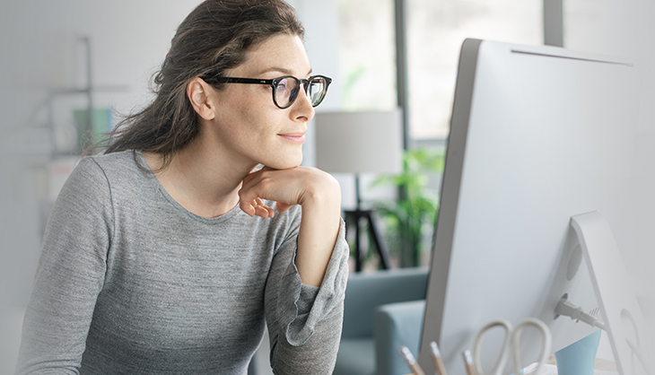 Frau mit Brille schaut auf einen Monitor